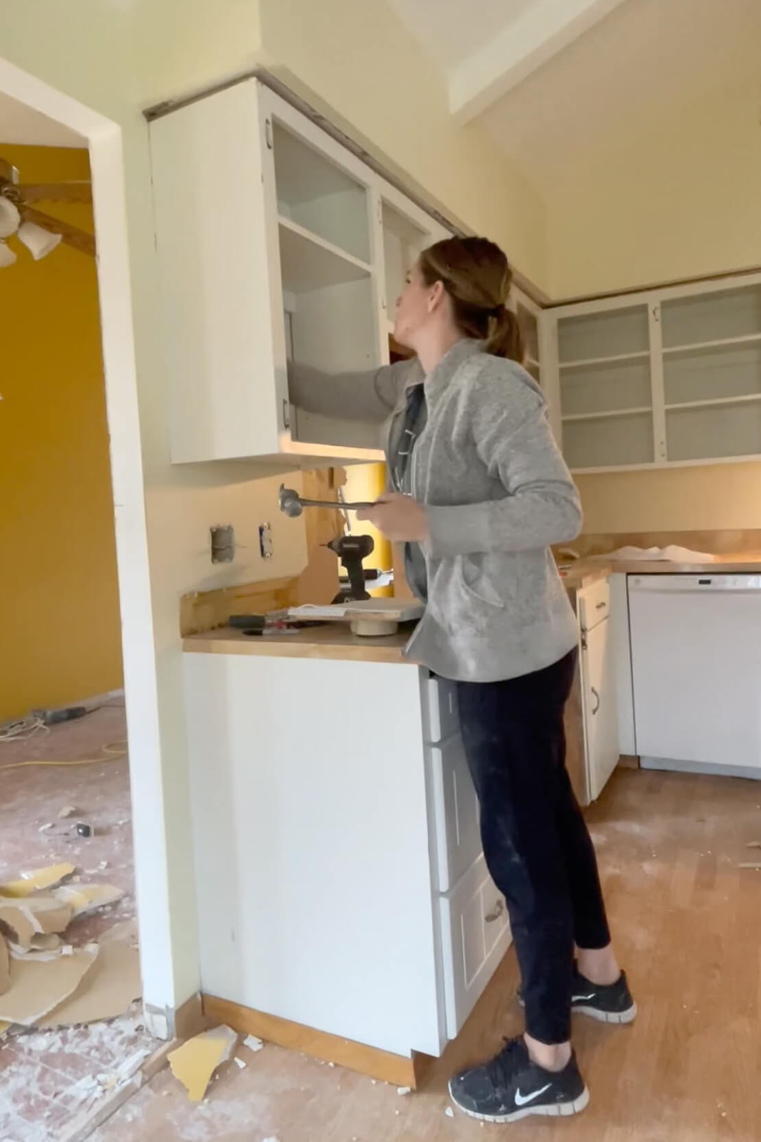 Woman removing old kitchen cabinets.
